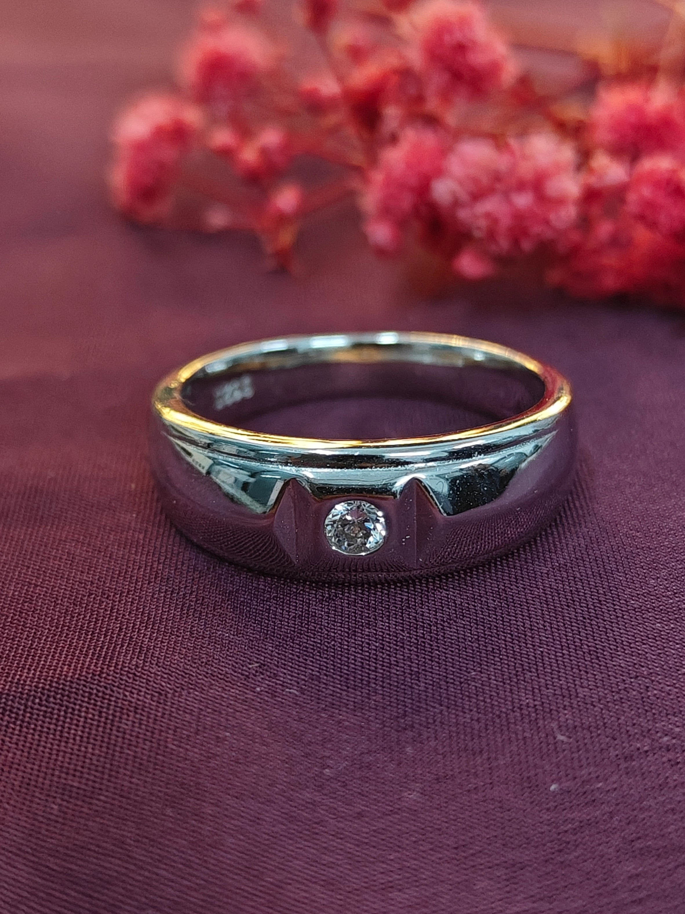 Gold and silver ring with a diamond on a purple fabric background